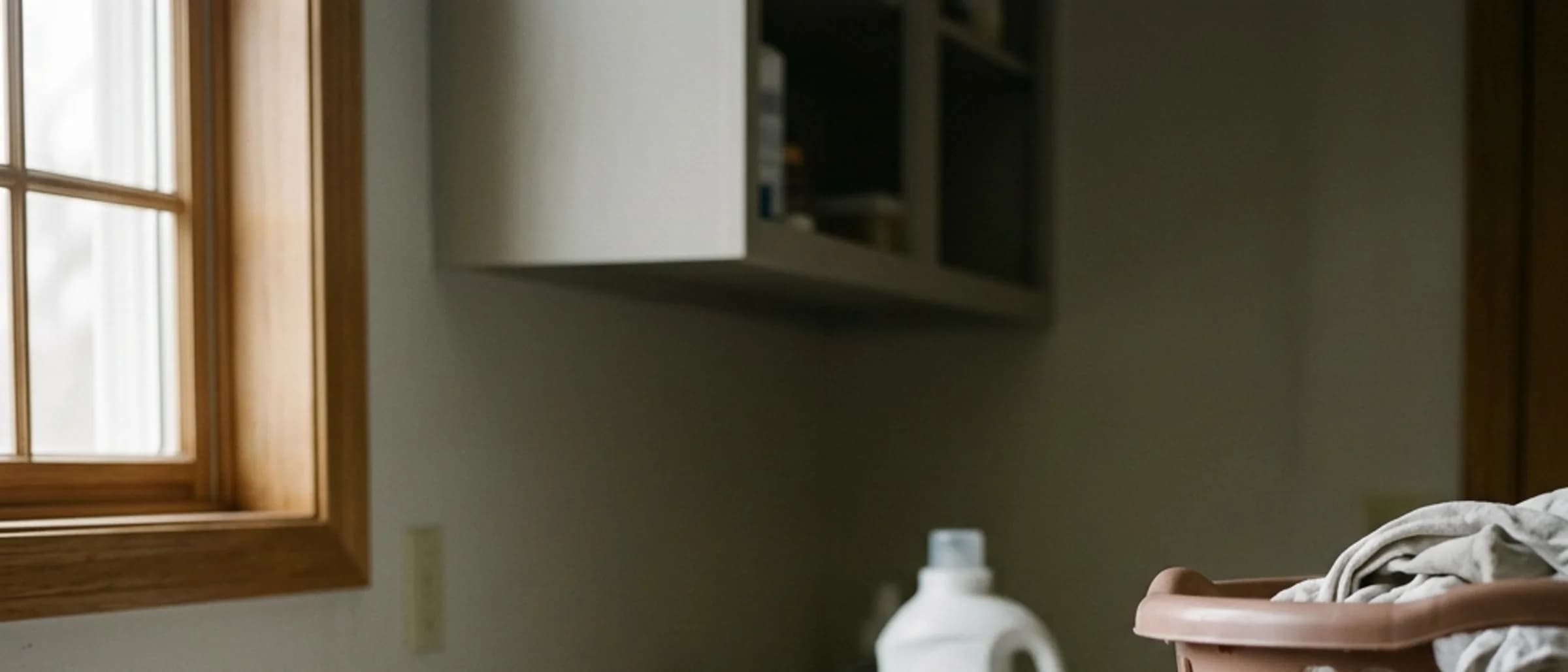 A stack of folded towels and a laundry basket on a utility room counter.